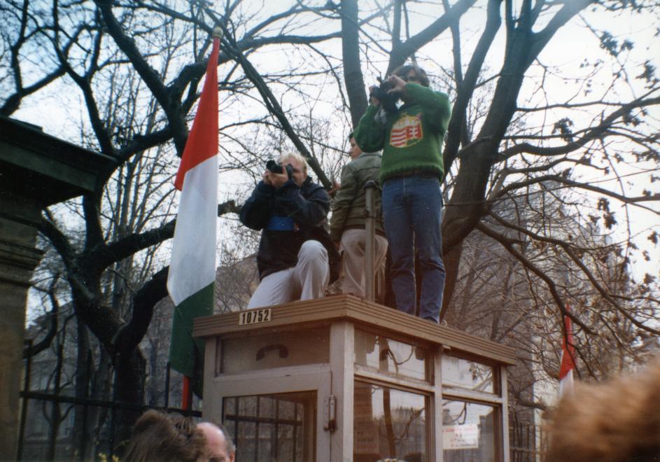 A Múzeum-kerti március 15-i ünnepség résztvevőit fényképezők a telefonfülke tetején, Múzeum körút a Nemzeti Múzeum bejáratától a Múzeum utca felé nézve