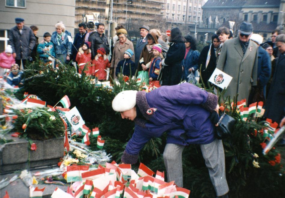A március 15-i megemlékezés és békés tüntetés résztvevői virágot helyeznek a Petőfi szobor talapzatára, Petőfi tér, háttérben a Március 15. tér, jobbra a Belvárosi templom