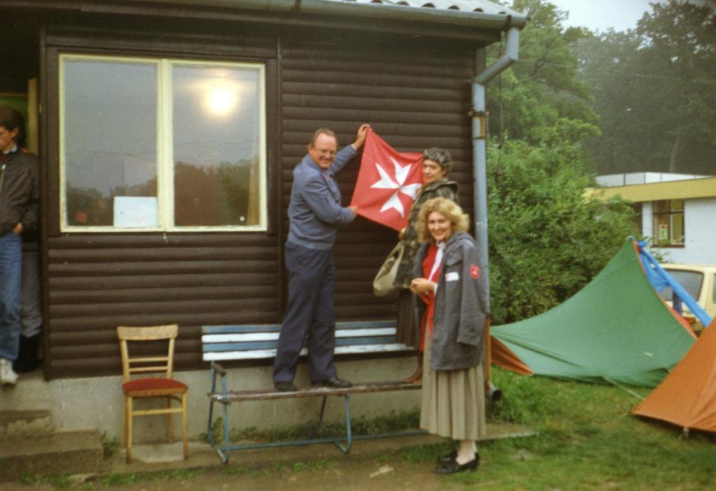 Csilla Freifrau von Boeselager, a magyar Máltai-Caritas szervezet társalapítója és a Máltai szolgálat egyik dolgozója zászlót helyez el a csillebérci menekülttáborban. Forrás: Archiv Wolfgang Wagner