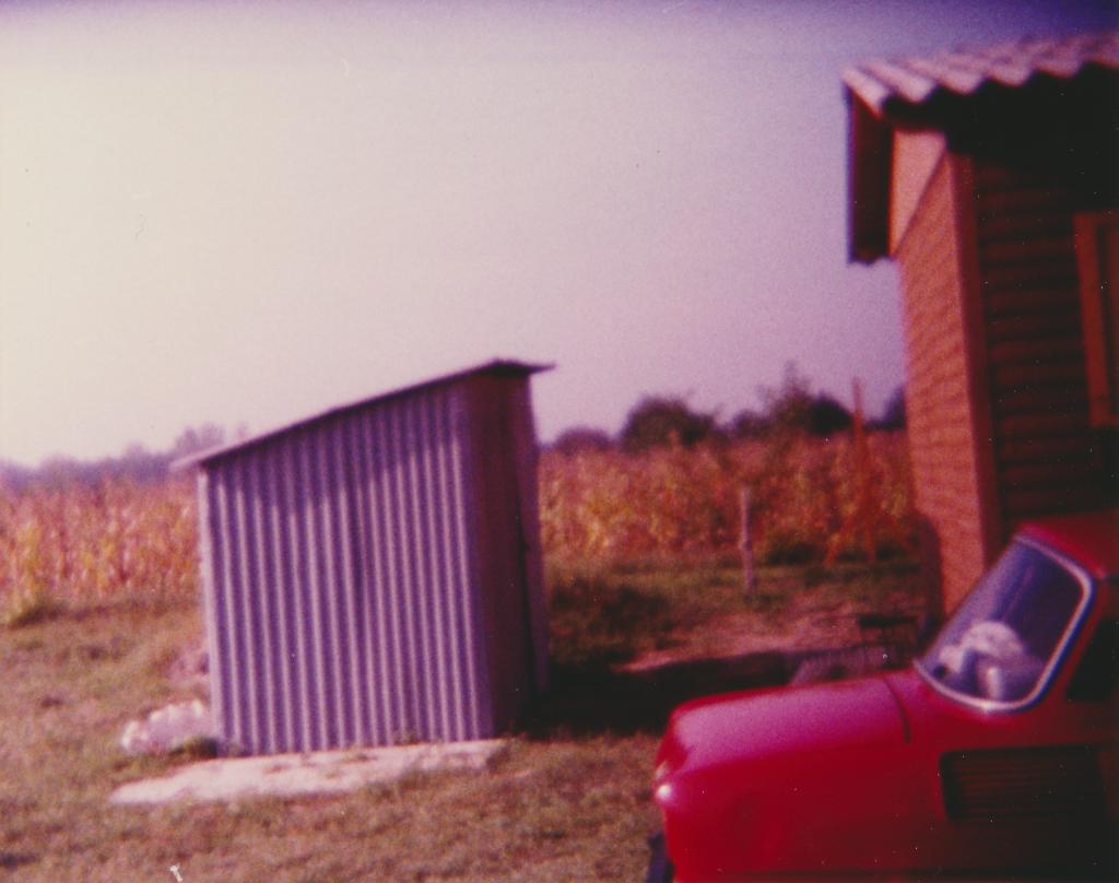 Könnyűszerkezetes faház, szerszámos bódé és Skoda 100 hátulról a kukoricás előtt